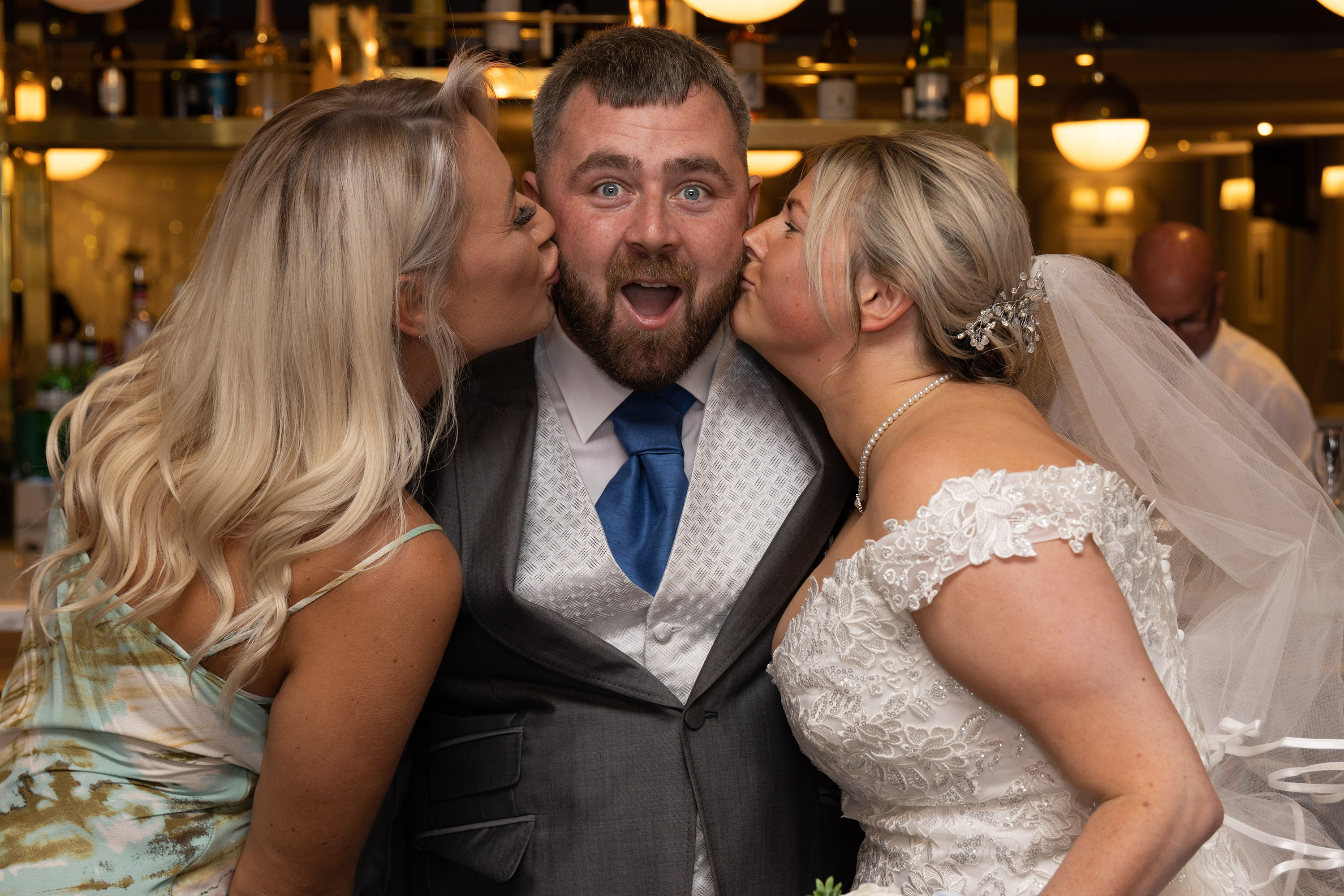 The groom gets a kiss from his wife and sister 