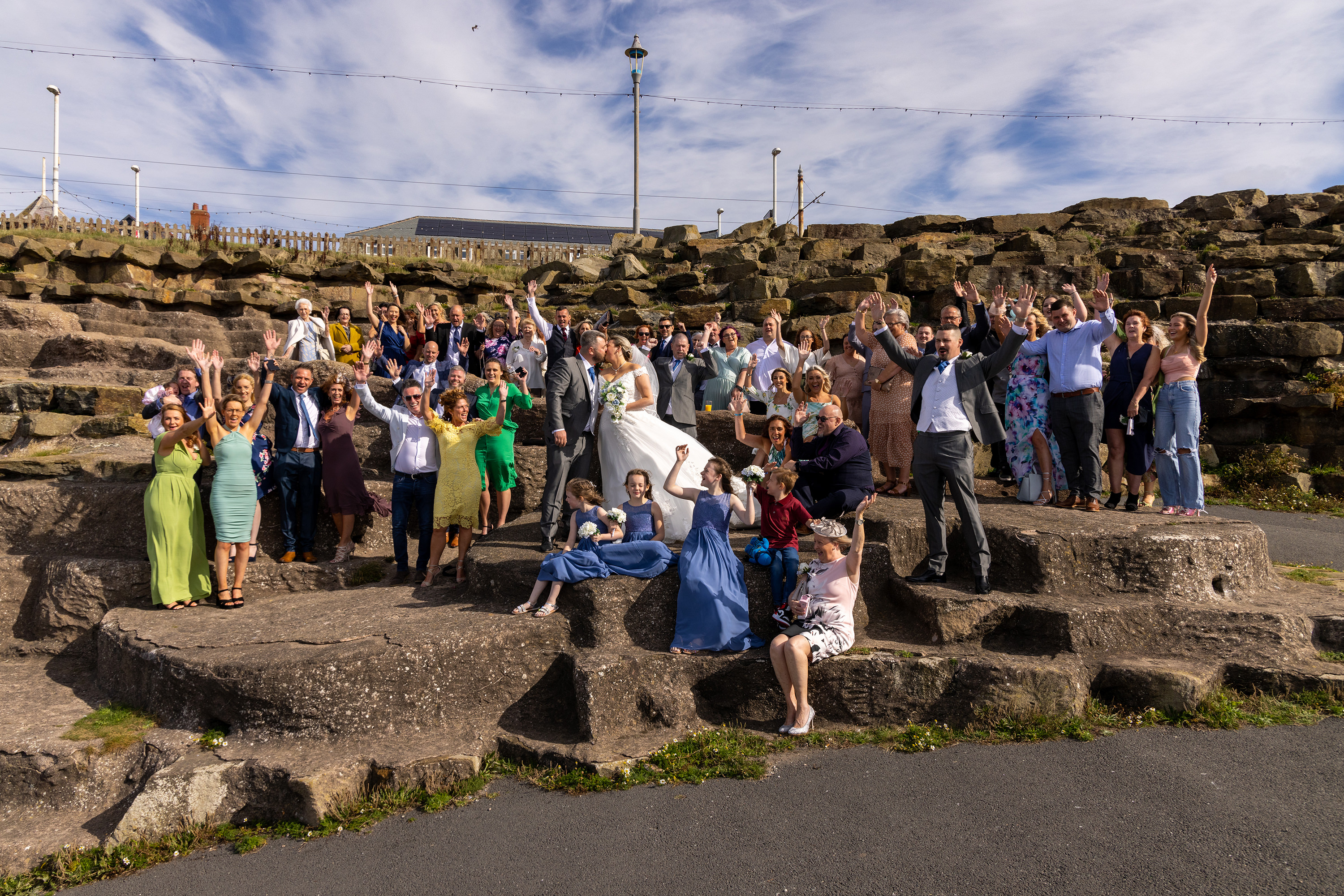 The bride and groom and their wedding guests pose for a photo on Blackpool Promenade