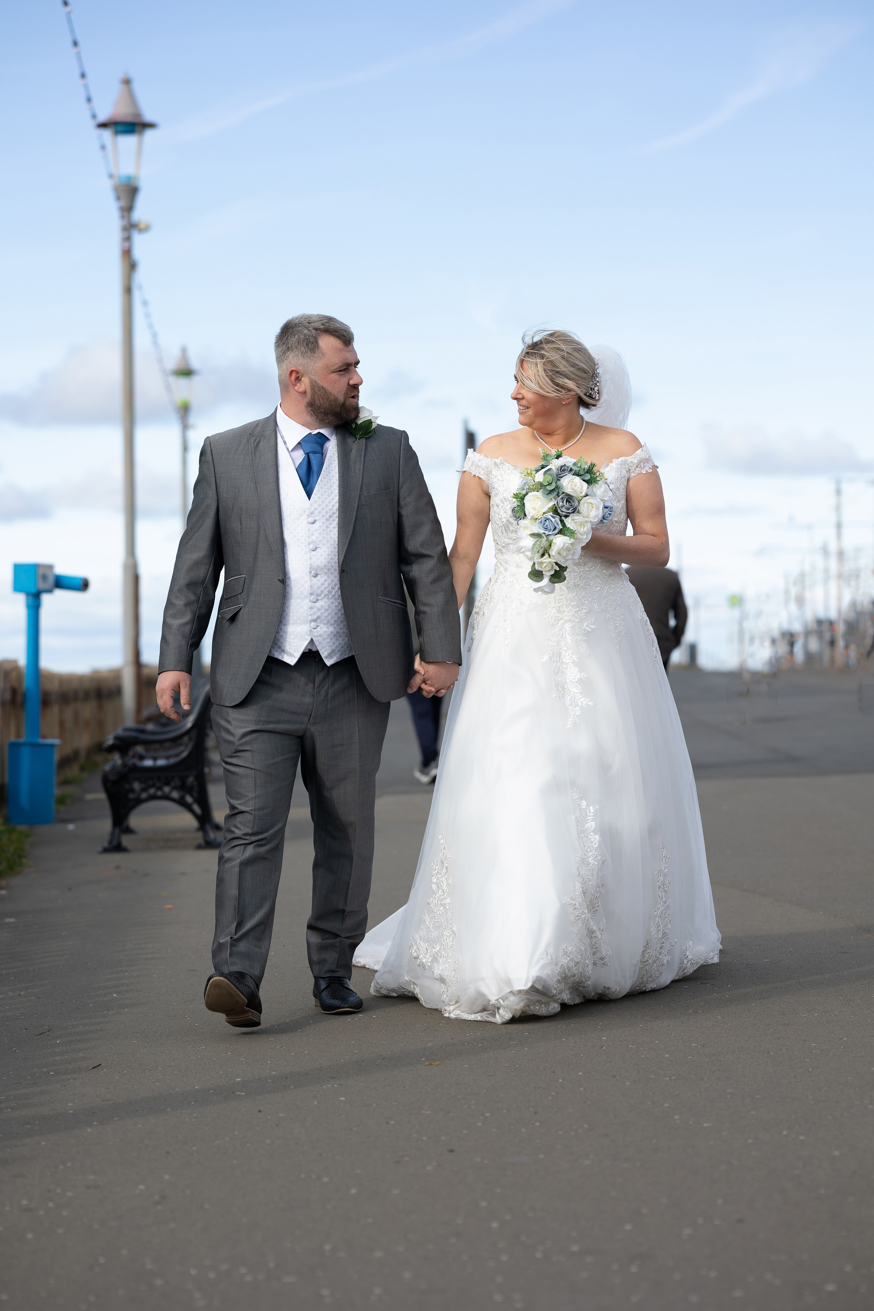 Kevin and Katie walk along Blackpool Promenade hand-in-hand after their wedding
