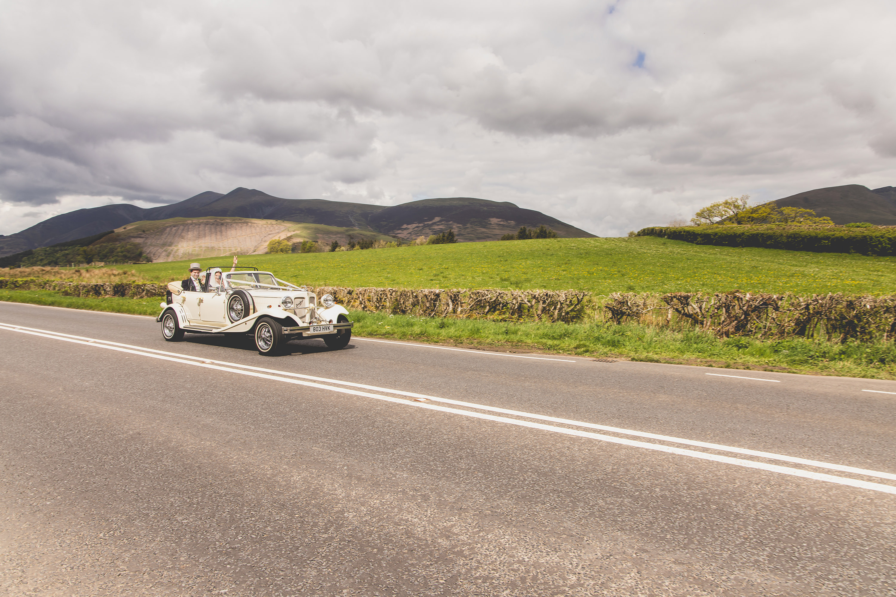 The bride and groom in the wedding car with blencathra mountain behind them