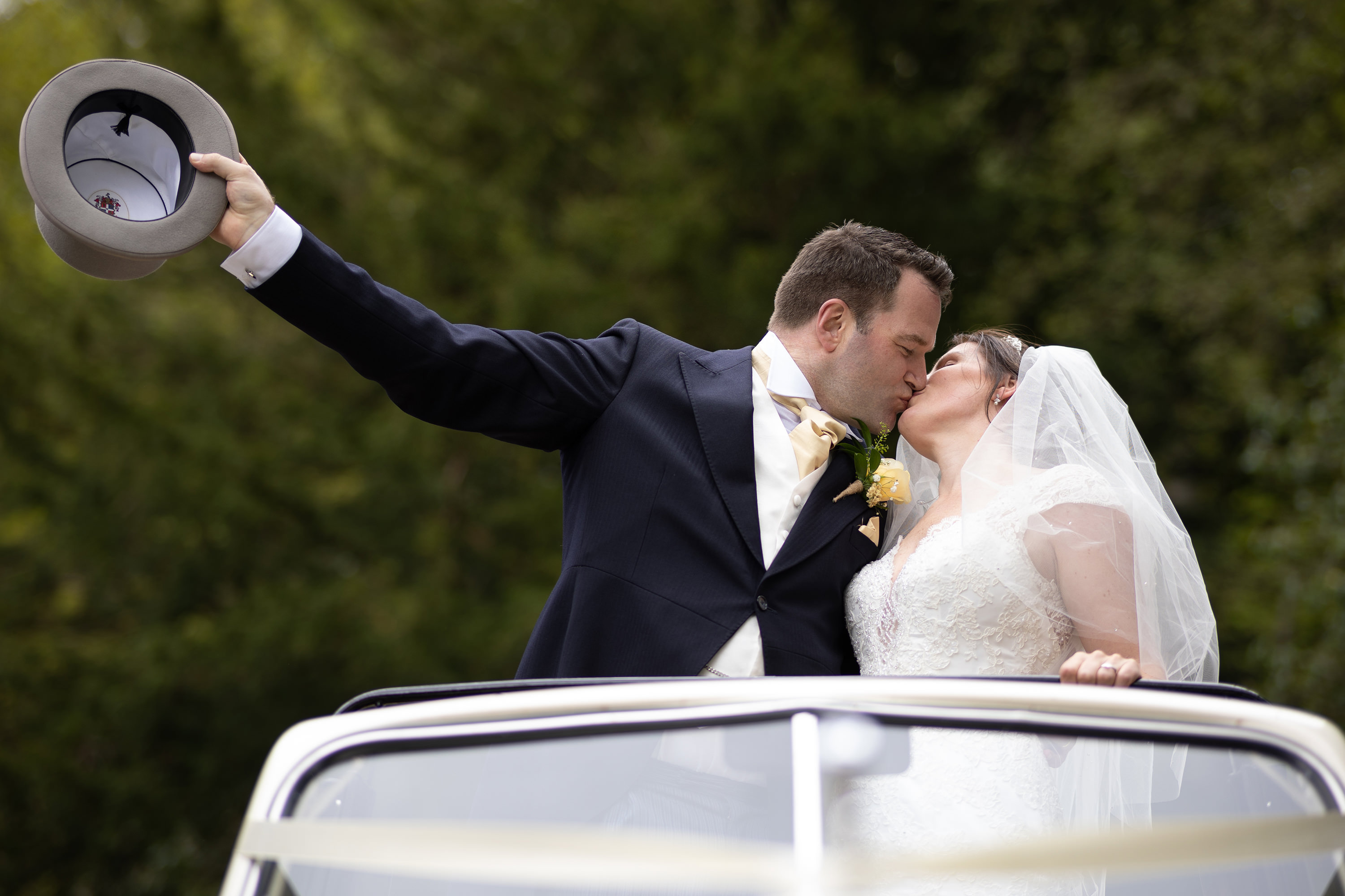 The bride and groom kiss in the wedding car 