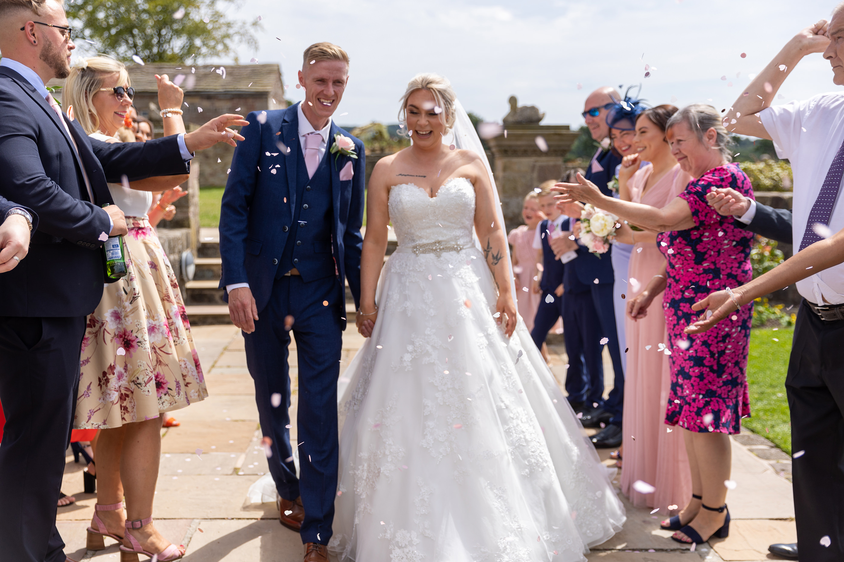 Friends and family throw confetti at the happy couple