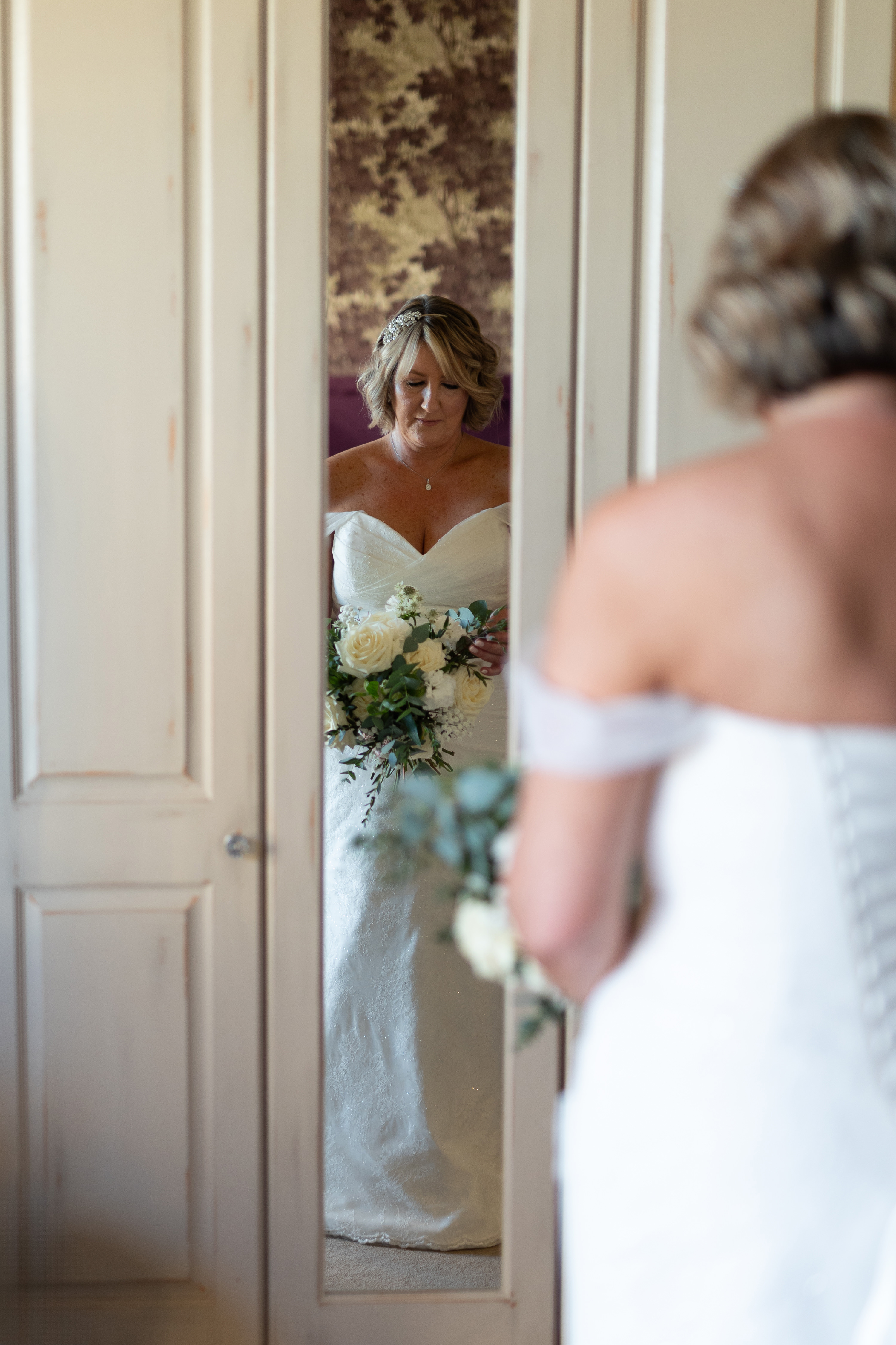 The Bride in her wedding dress looking down at her bouquet 