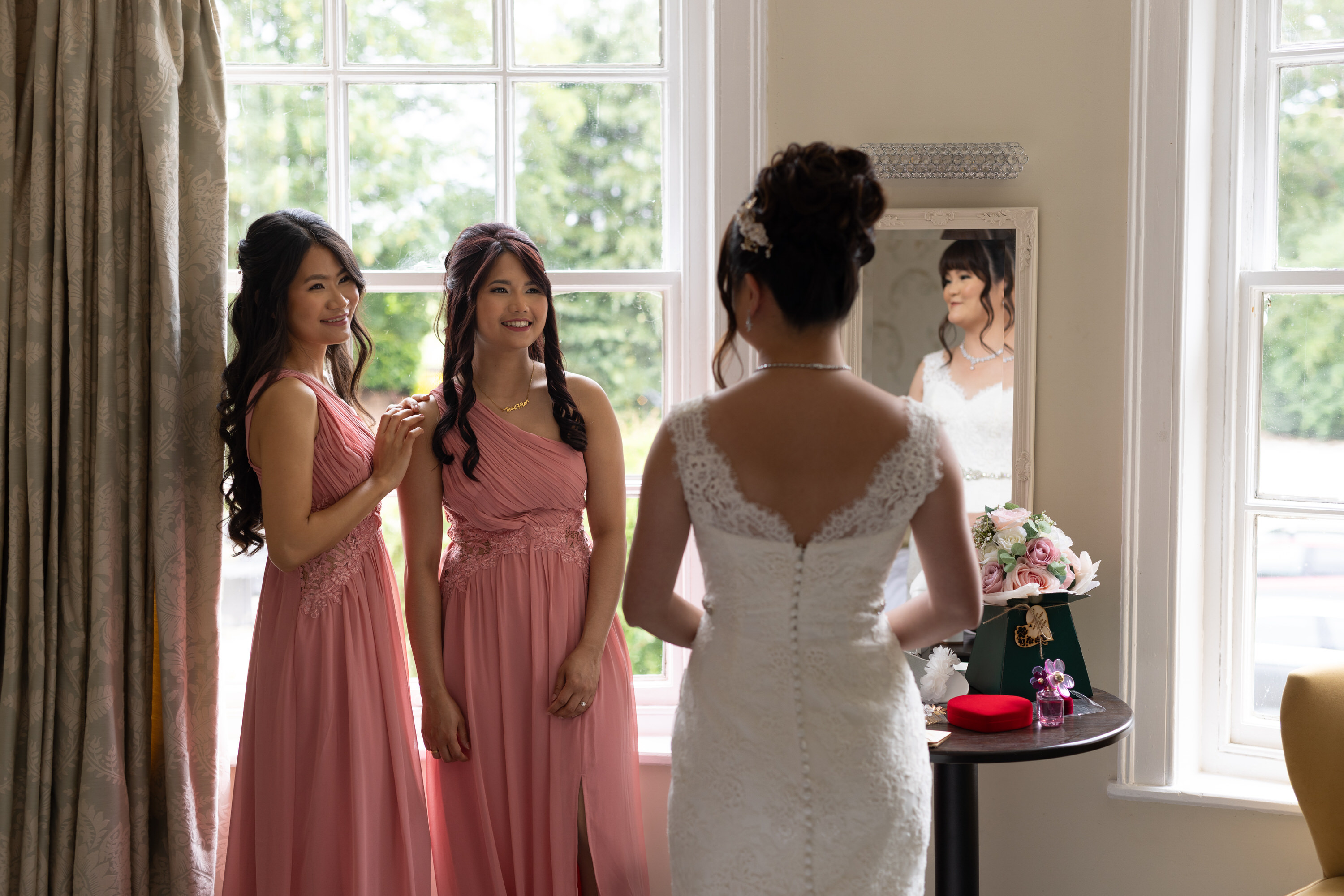 The bridesmaid is looking at the Bride in her wedding dress 
