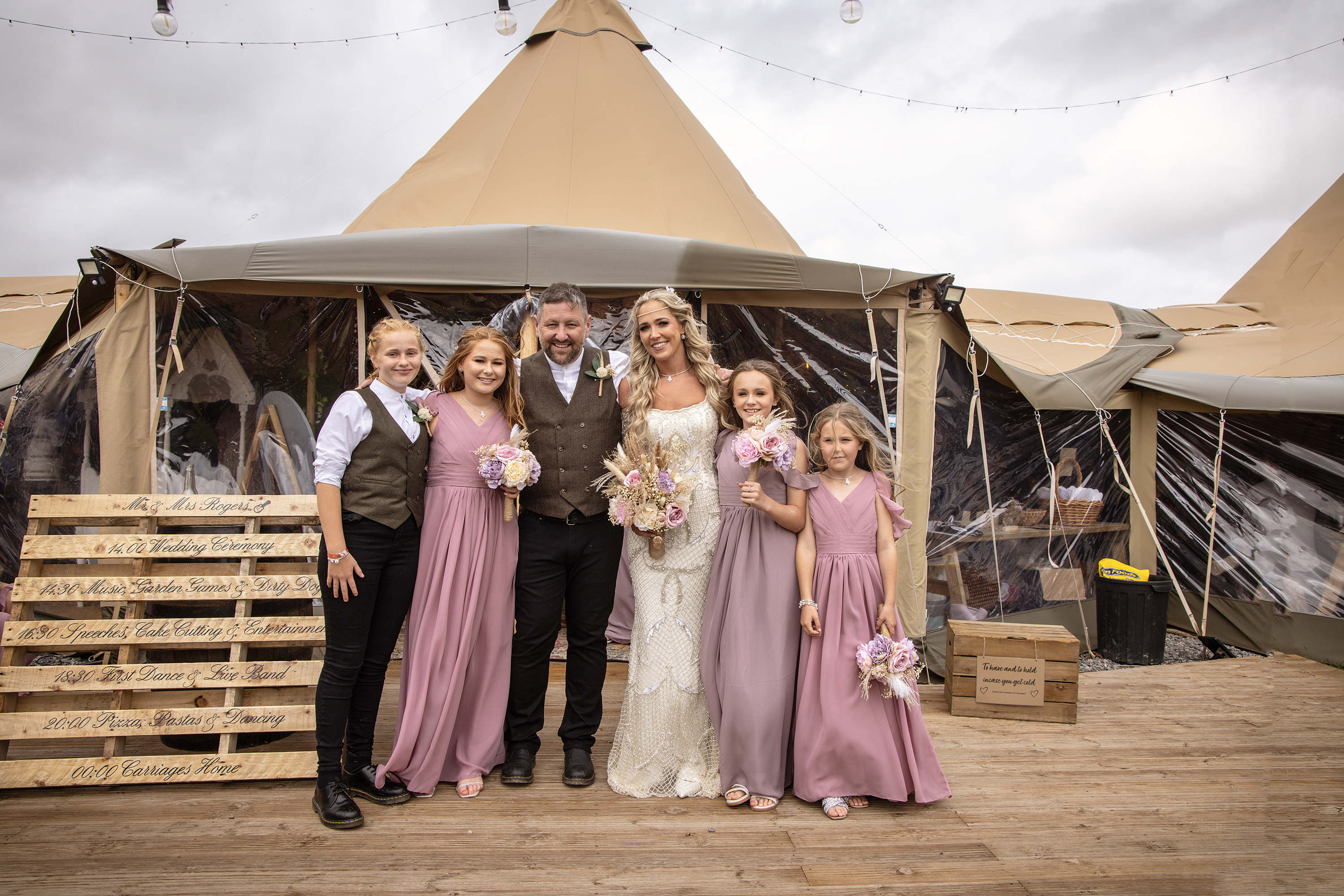 The bride and groom have a family photo with their children 
