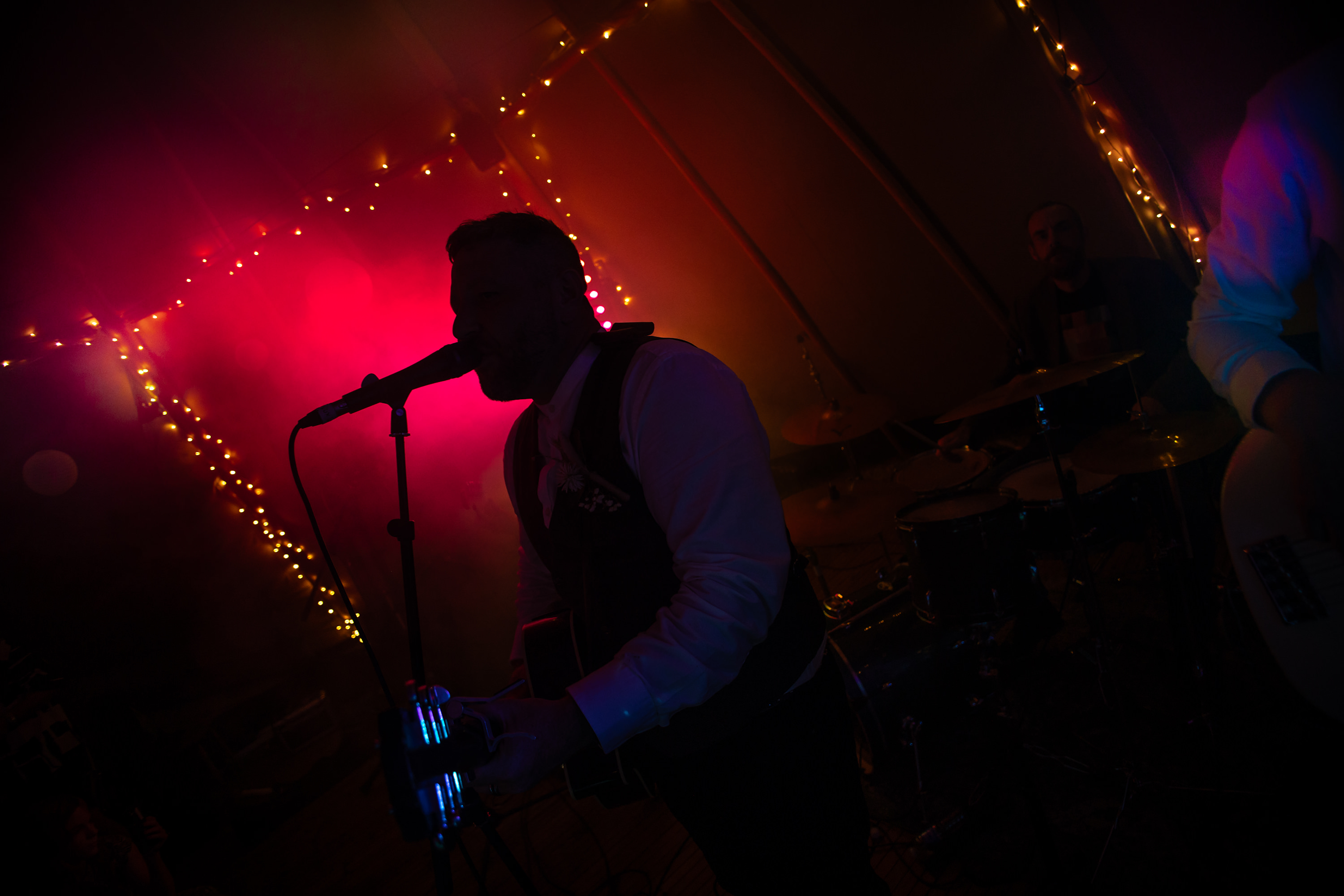 The groom silhouette is against the party lights 