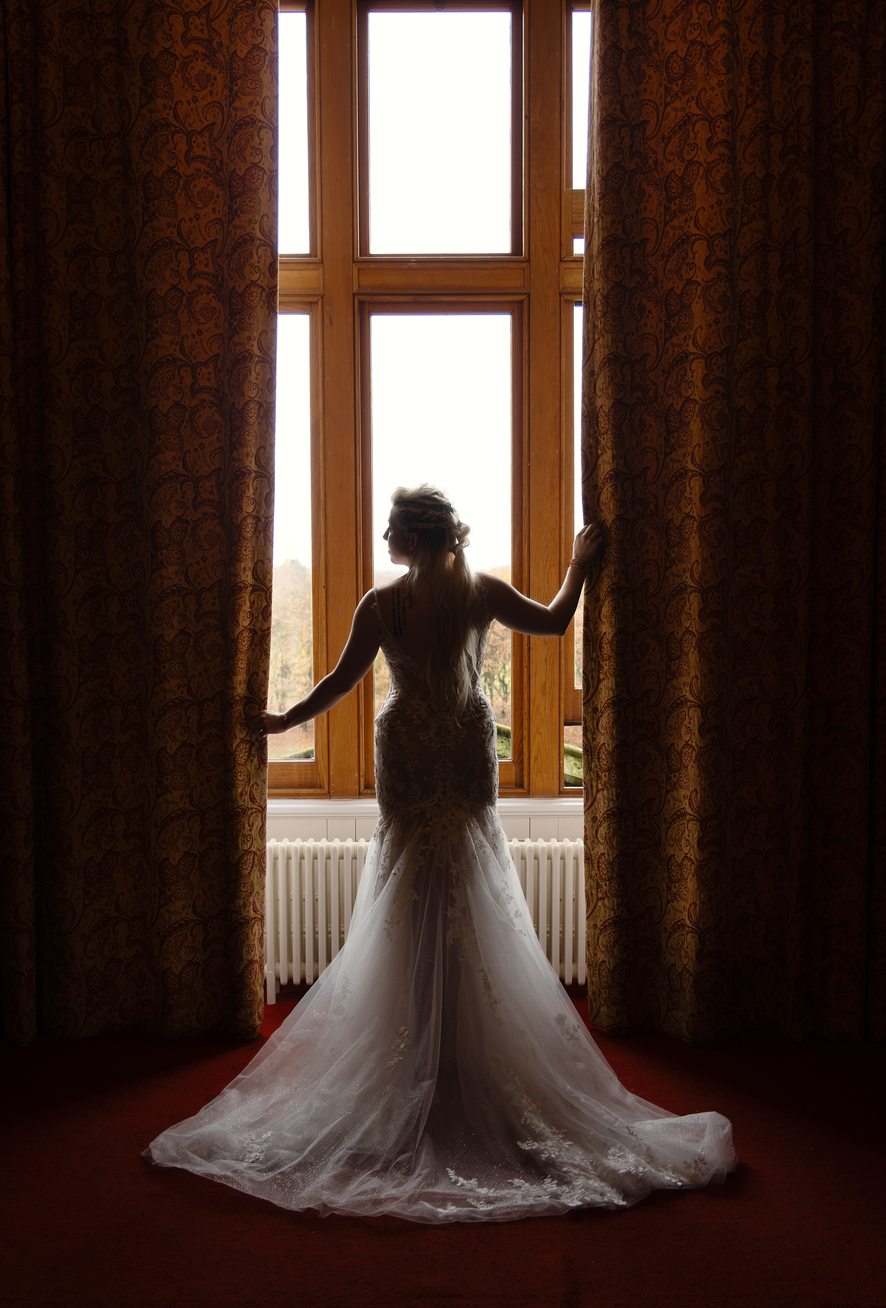 The Bride takes a moment to pose in front of the window at Allerton Castle 