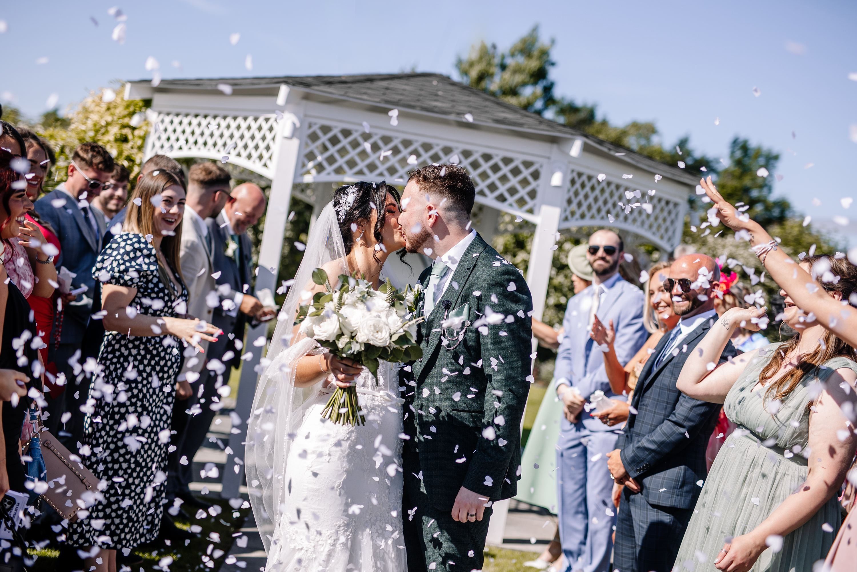 The bride and groom kiss under the confetti
