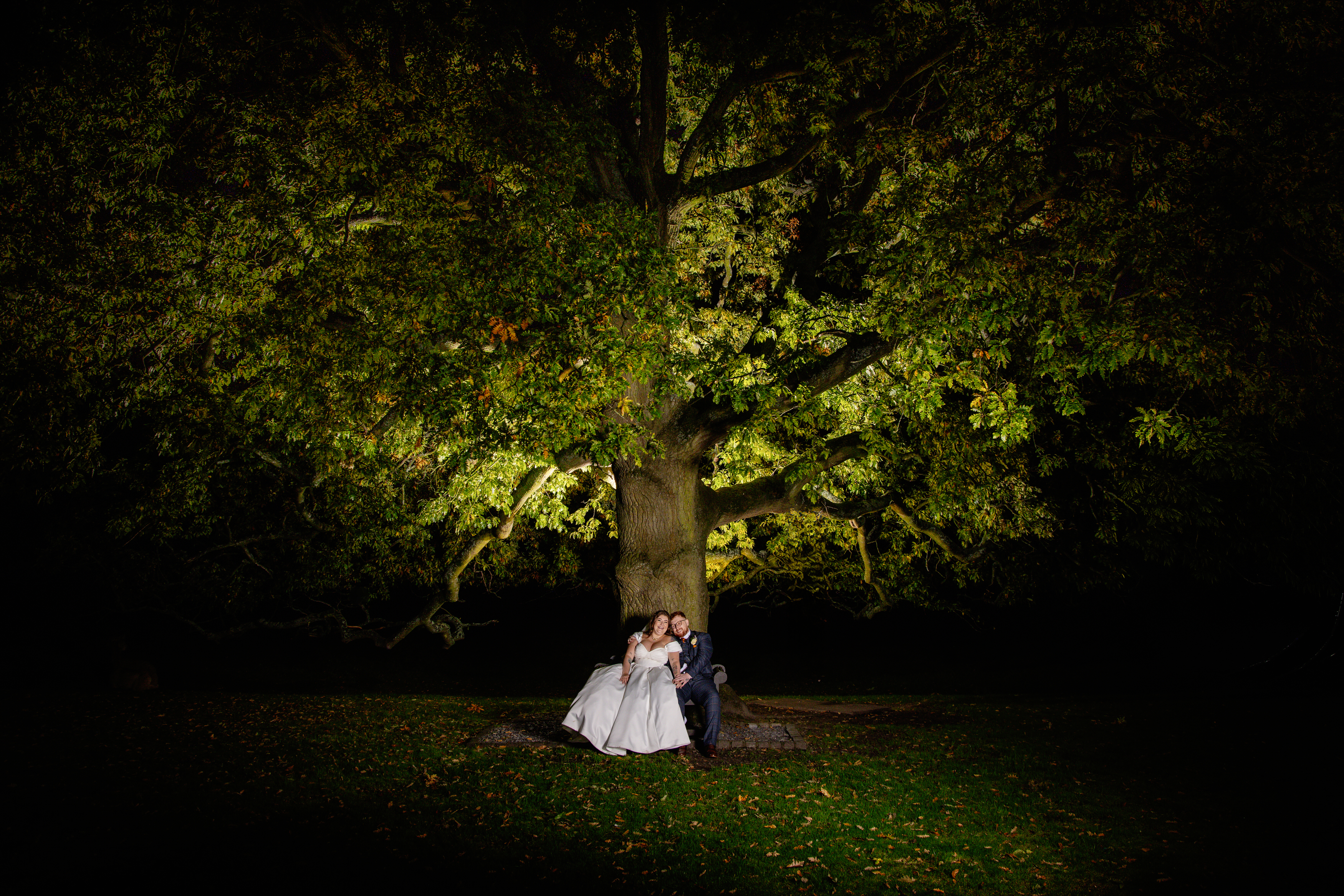 A happy couple sit under the old oak tree 