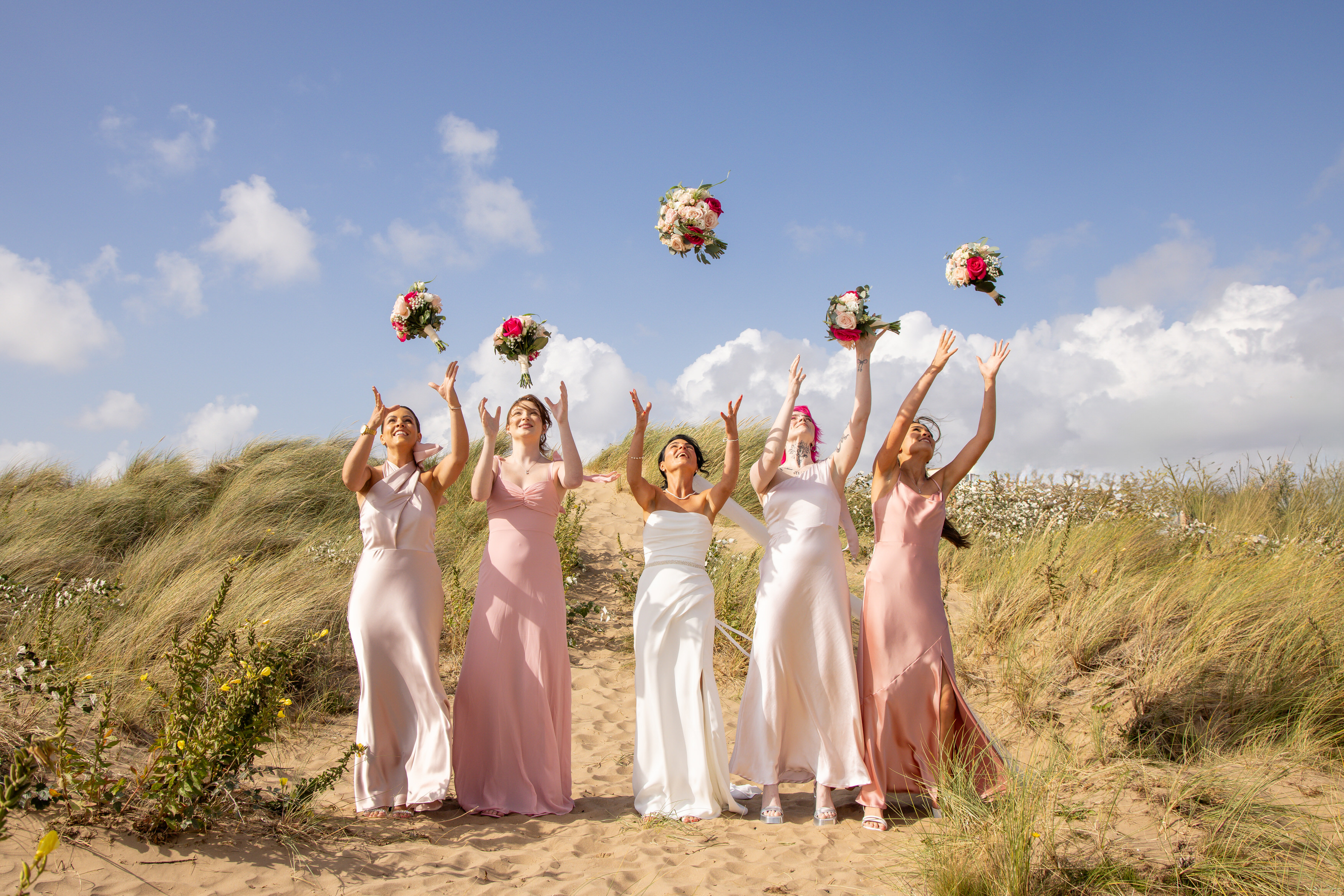 The bride and her bridesmaids throw the bouquets in the air 