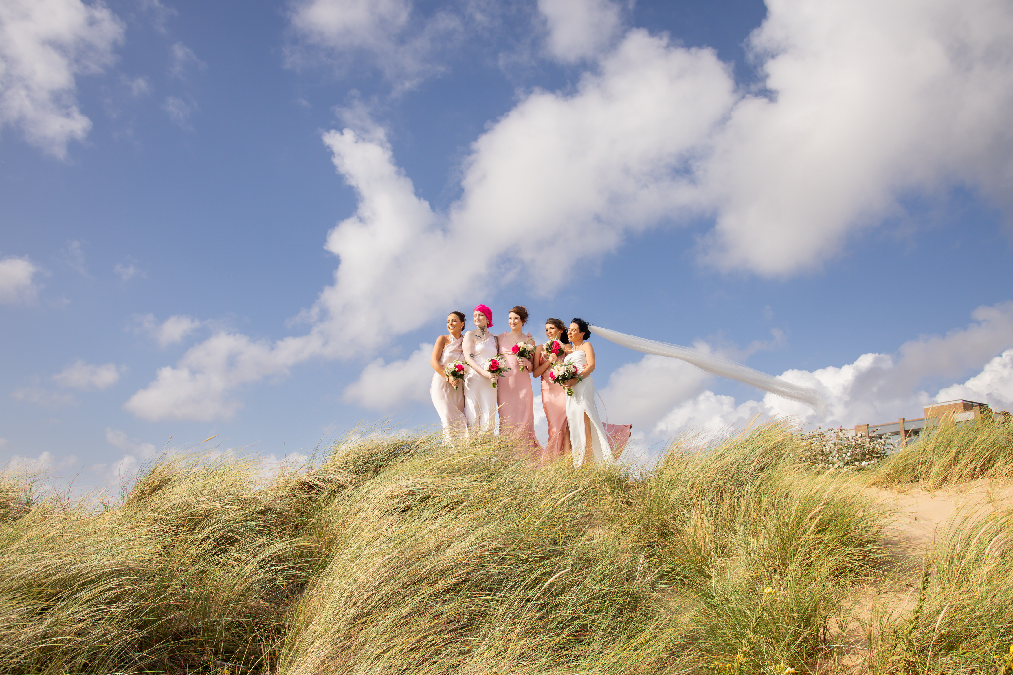 The bride and her bridesmaid stand on the sand dunes 