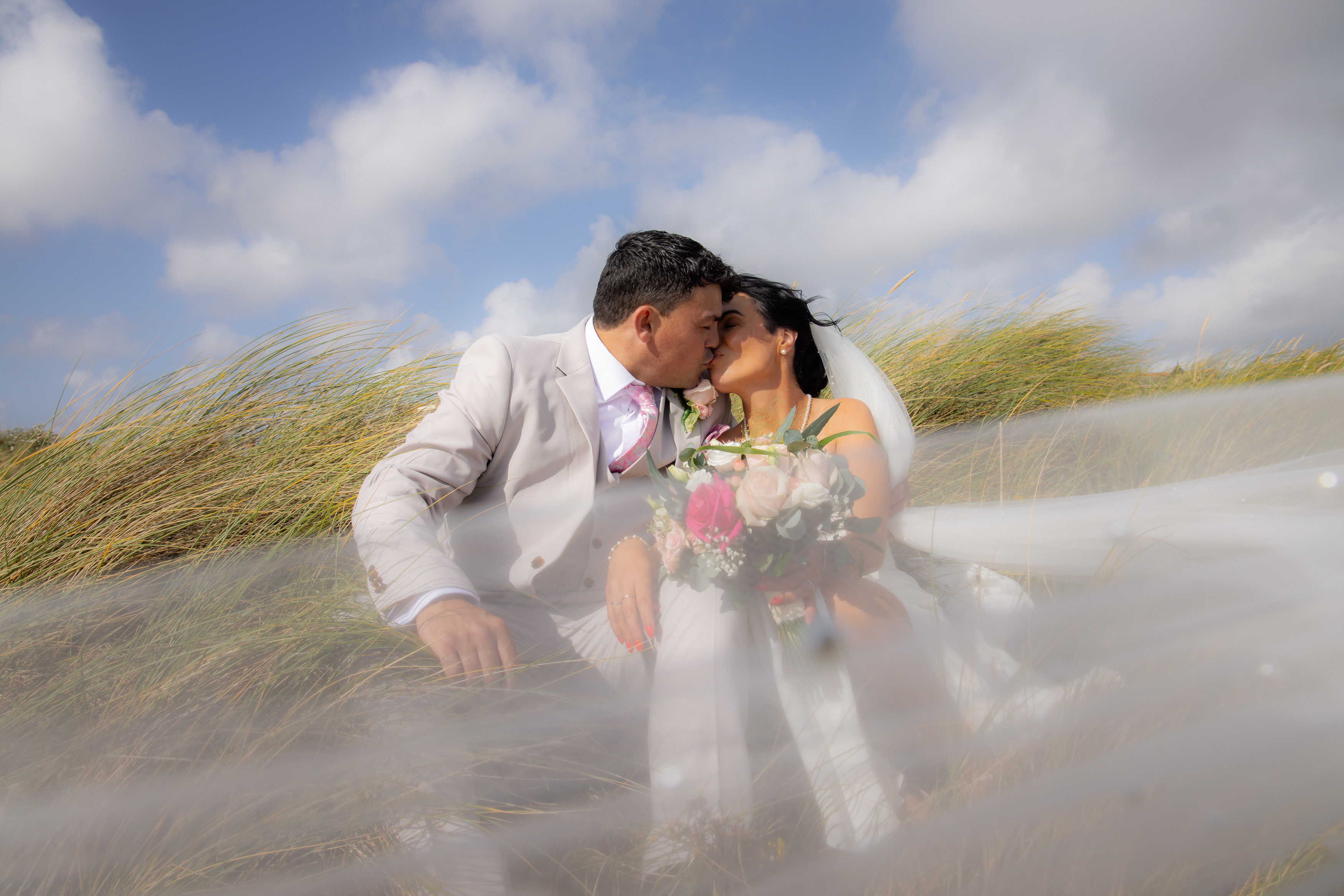 Sara and Andrew sit on the sand dunes 