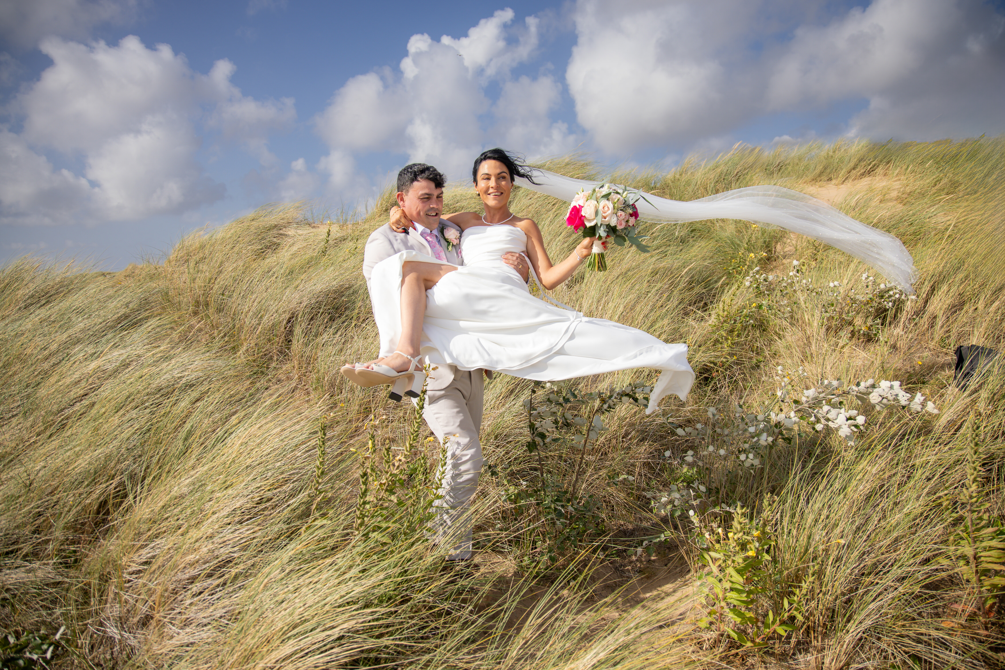 Andrew carriers his bride Sarah down the sand dunes