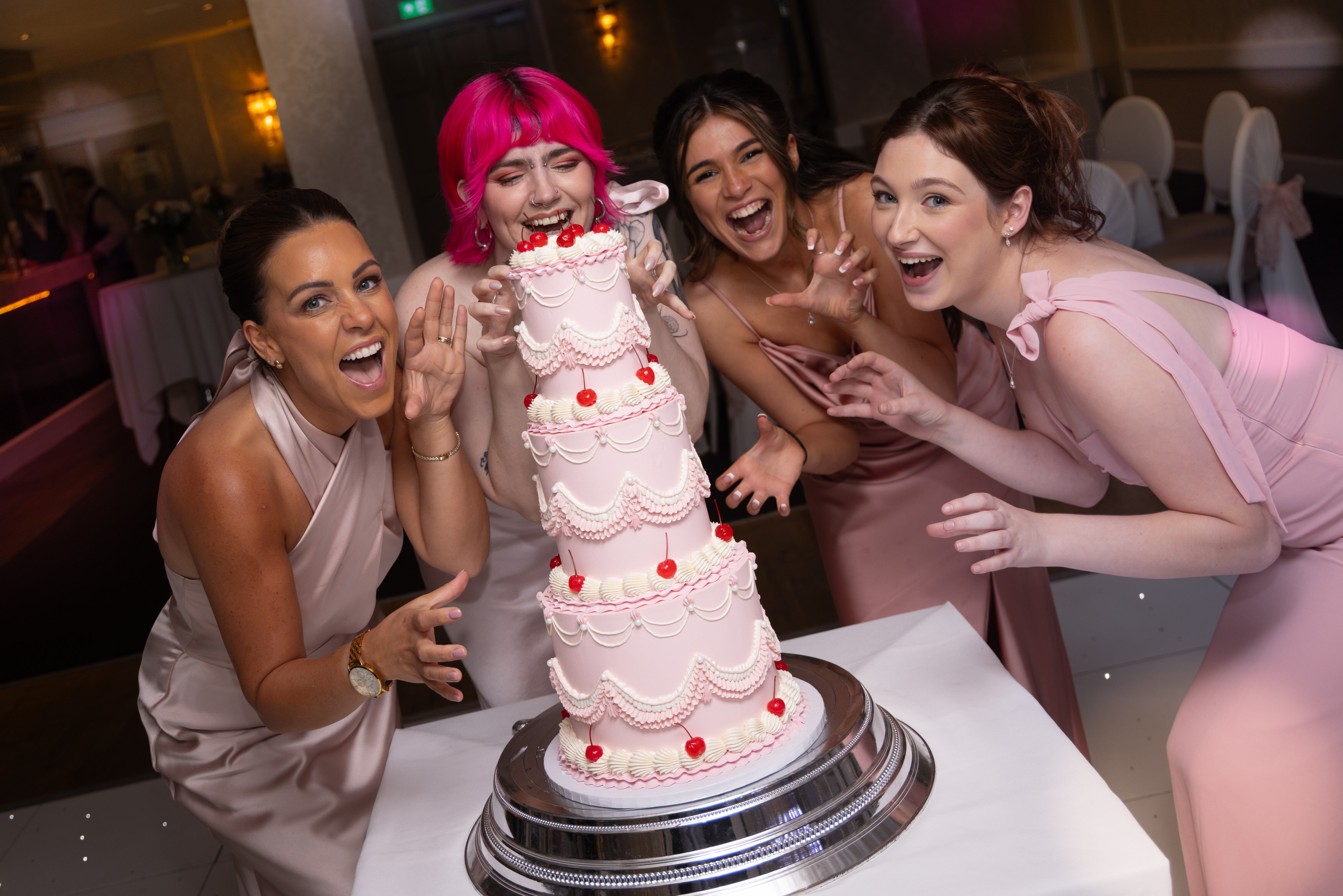 The bridesmaids pretend to eat the wedding cake 