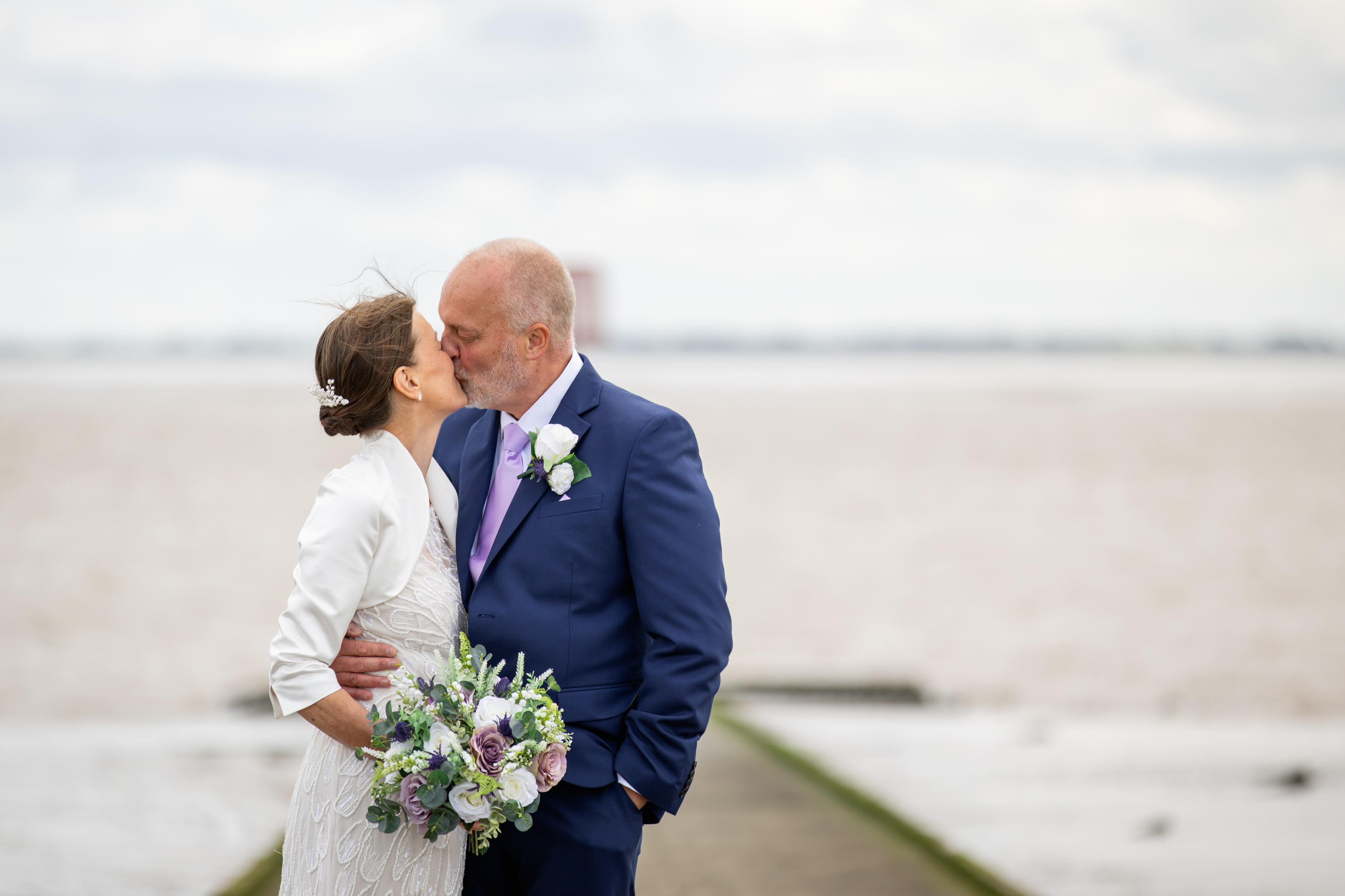 The bride and groom have a kiss on lytham jetty 