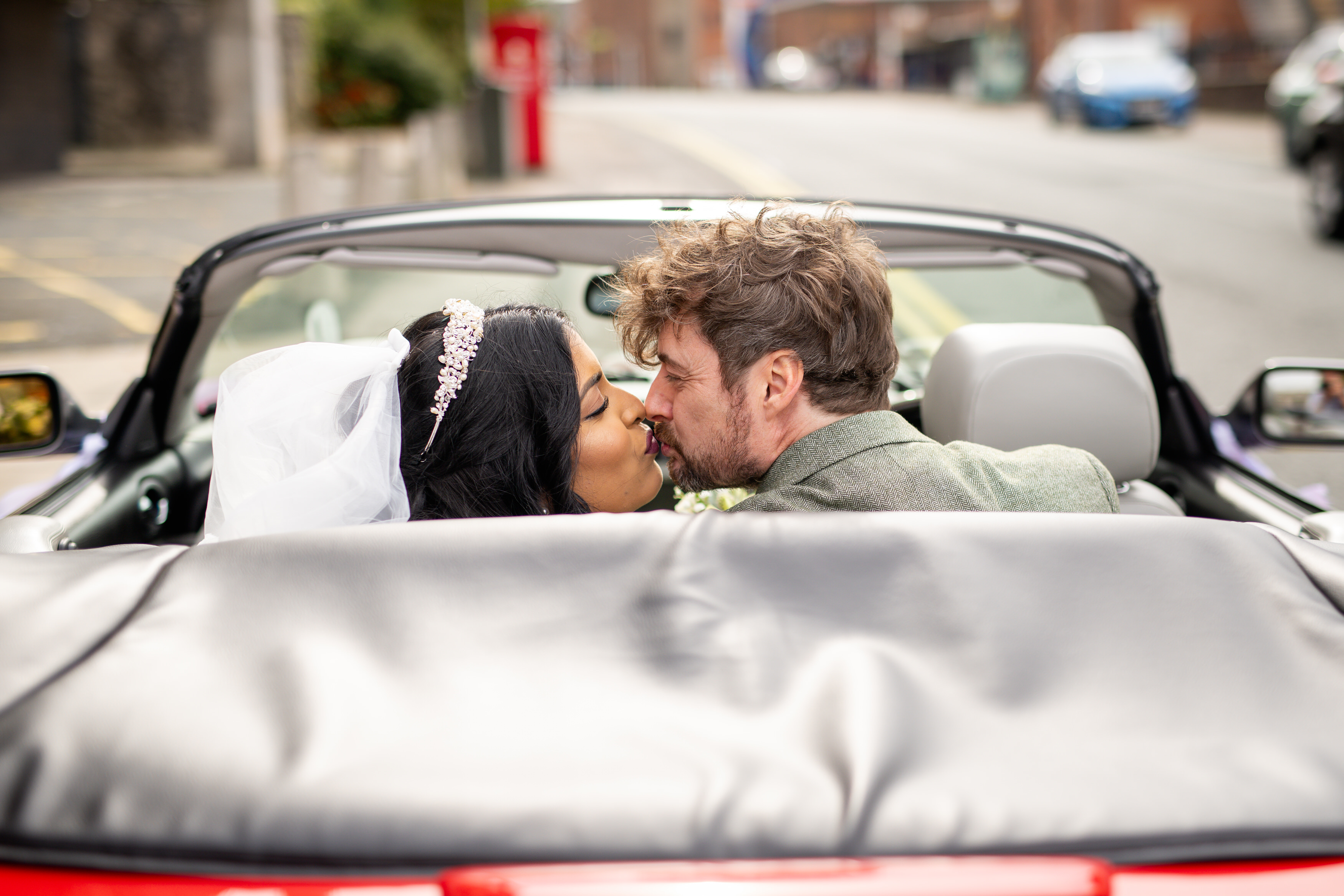 Udara and Tony kiss in the back of the red Ferrari 