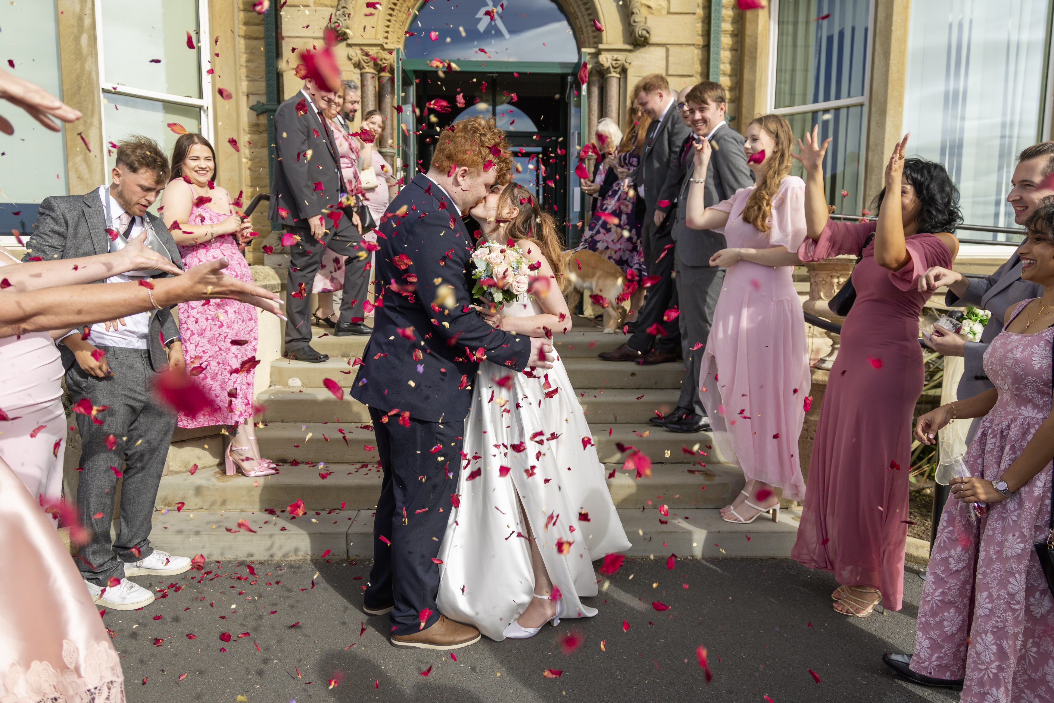 The wedding guests throw confetti over the bride and groom 